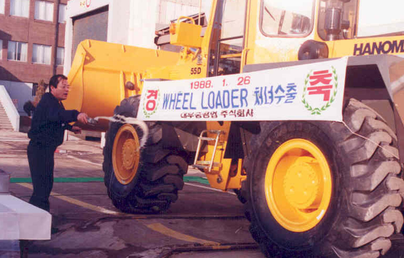 Historical photo of a large Doosan wheel loader with a ceremonial banner